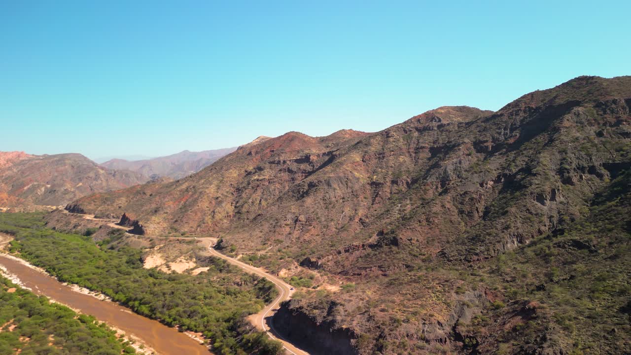 Vista aerea di una strada tortuosa tra montagne aride e un fiume