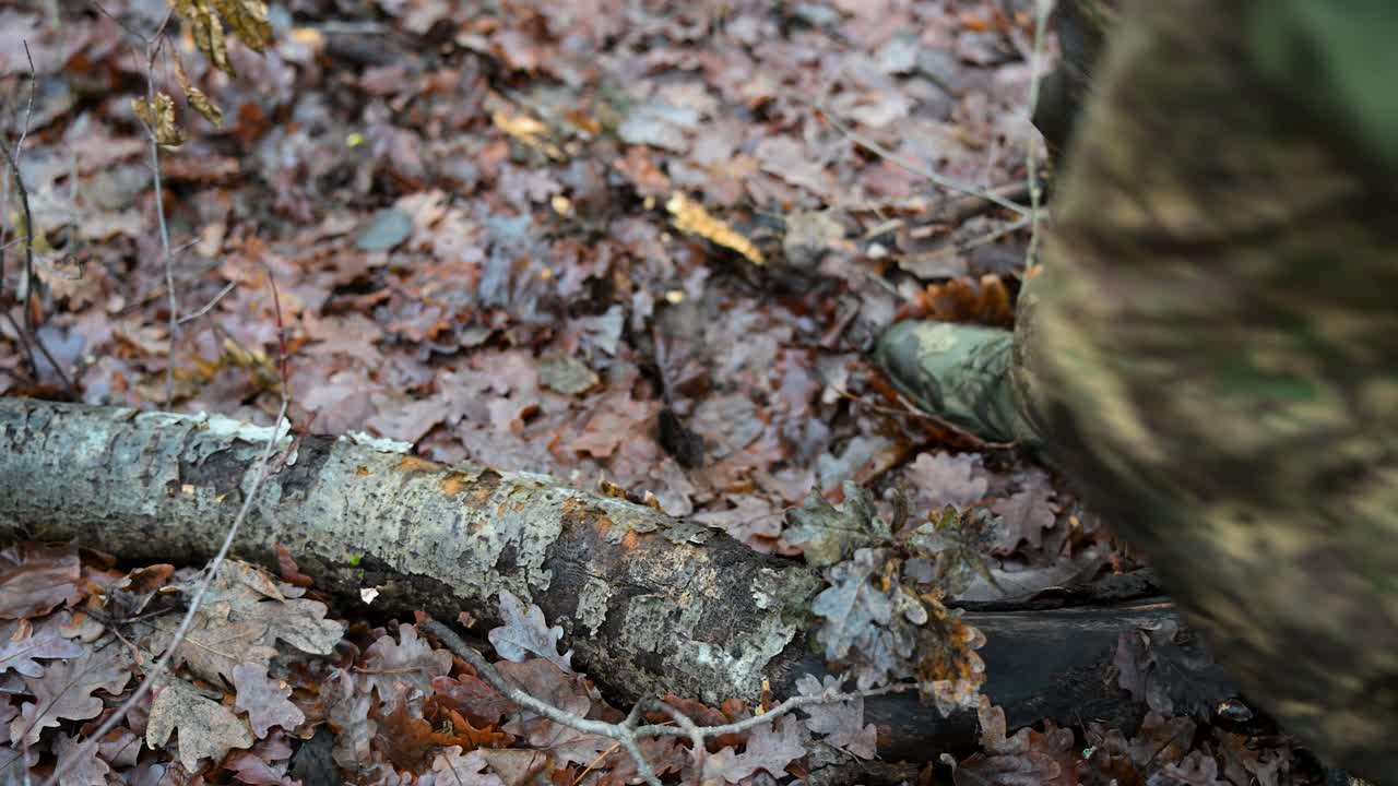 Close-up on the combat boots of a soldier moving through a wet, leafy forest in Ukraine. A foreign volunteer from the International Legion is on a tactical training for the Ukraine-Russia war