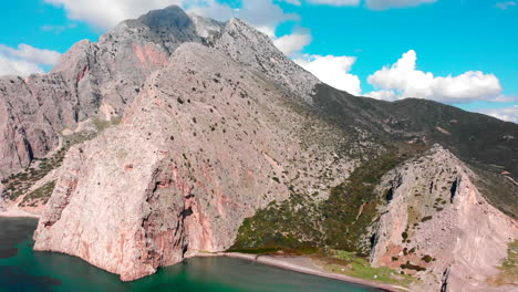 Beautiful Moutain Landscape Surrounded By Turquoise Blue Water With A Bright Blue Sky On The Background In Greece. - aerial drone shot