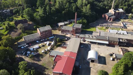 vista aérea de un mercado de agricultores en tiendas blancas que venden productos en una zona industrial de aspecto rústico