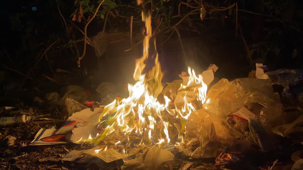 basura quemada con llamas amarillas anaranjadas en la calle dhaka por la noche