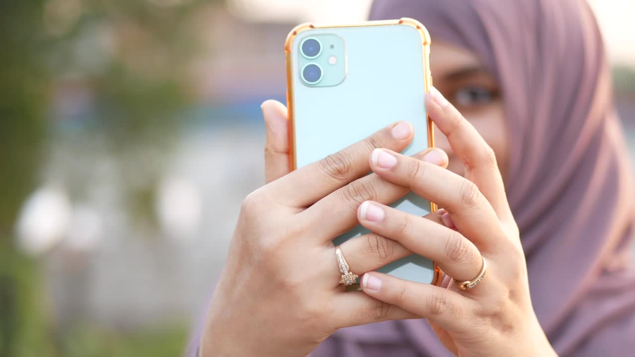 mujer con hijab tomando una selfie con un teléfono inteligente