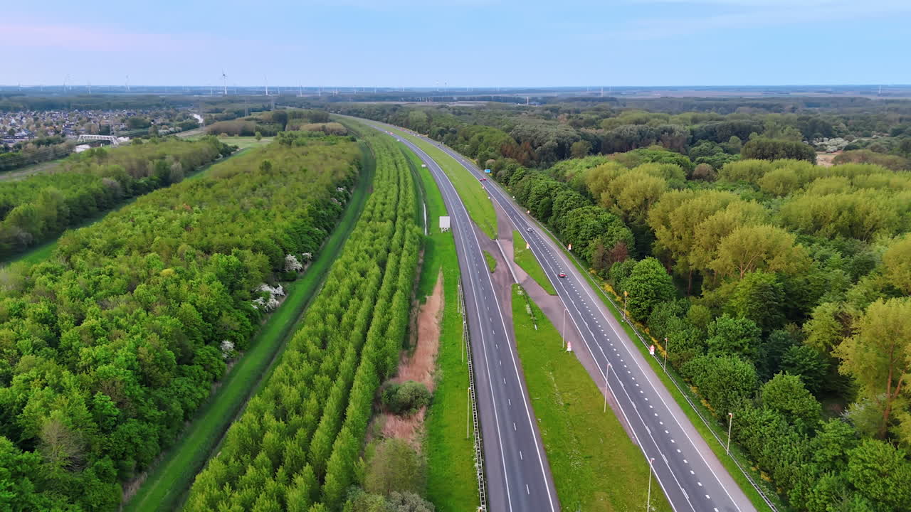Lush green landscape along the highway. Trees line the highway, showcasing vibrant greenery alongside the smooth asphalt road in a peaceful rural setting
