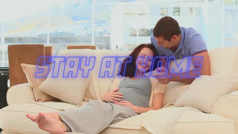 animation of blue neon words stay at home over caucasian couple looking at pictures