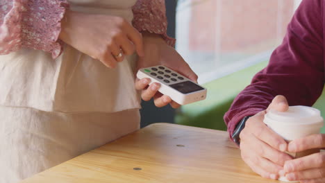 primer plano de un hombre haciendo una compra sin contacto en una cafetería usando un reloj inteligente