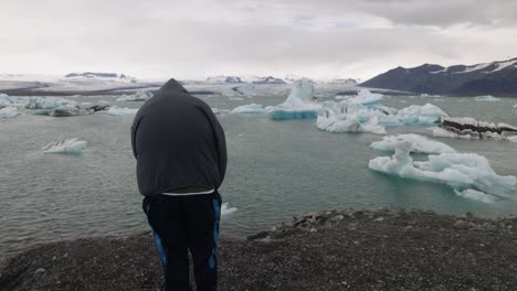 laguna glaciar en islandia con un hombre mirando y un video cardán caminando detrás