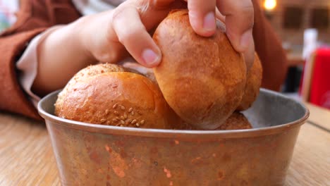 woman taking a bread from a bowl