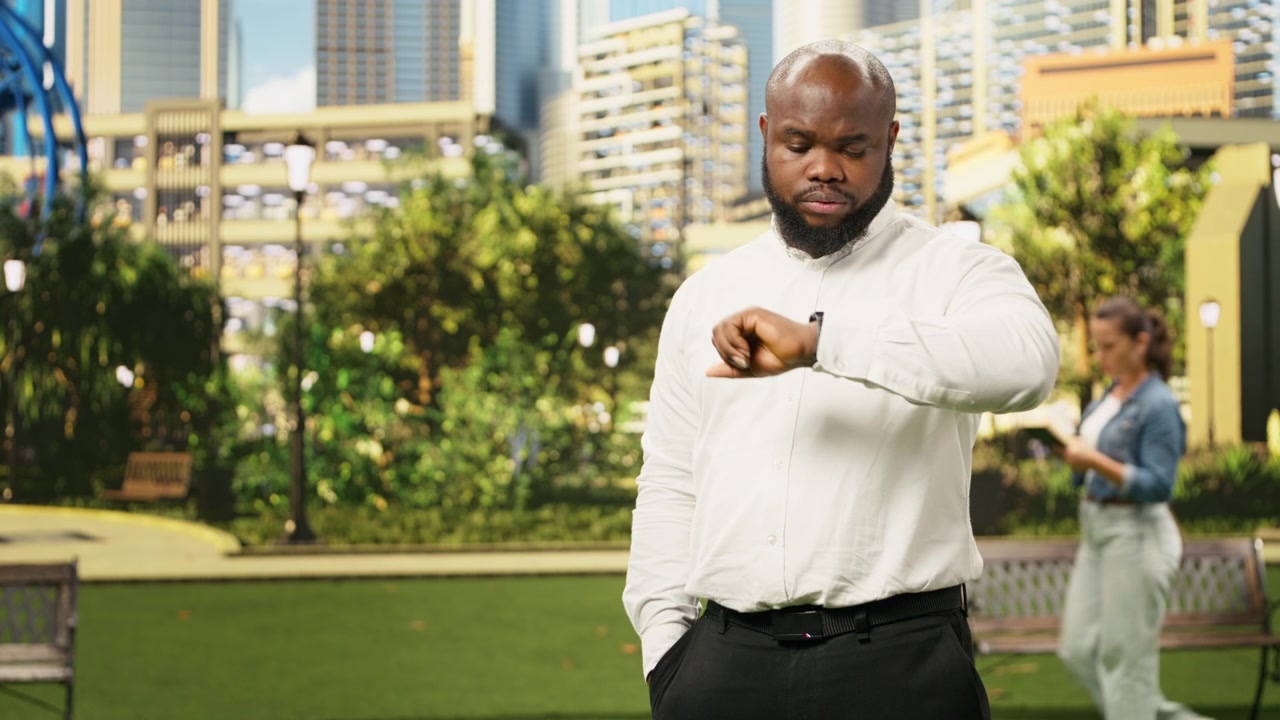 Concerned businessman checking time on smartwatch while standing in city park