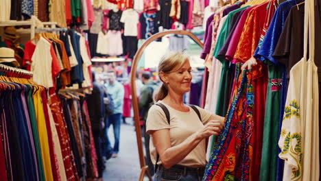woman browsing colorful clothes at a vibrant market