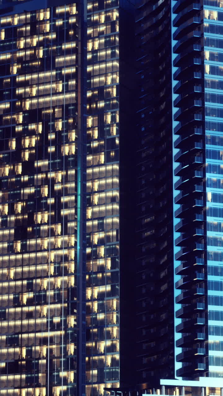 Tráfego distante ilumina o horizonte da cidade contra a fachada de vidro noturna