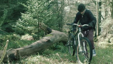 Young-athletic-teen-grabs-bike-and-sets-off-cycling-within-forest