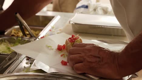 man making a mexican taco, and wrapped with a paper at shop