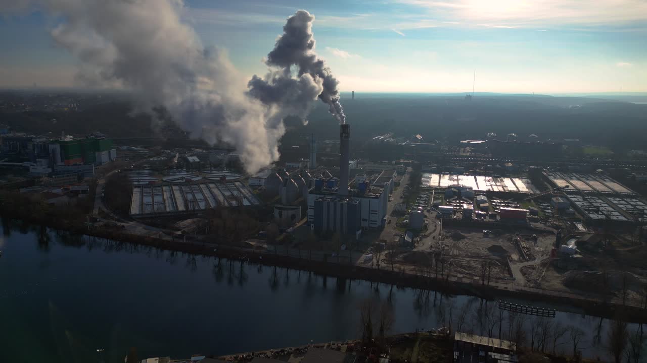 Industrial chimneys emitting white smoke over city skyline under blue sky, concept of pollution. Perfect aerial view flight panorama overview drone
