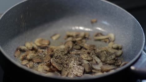 adding spices on a frying mushrooms in a pan