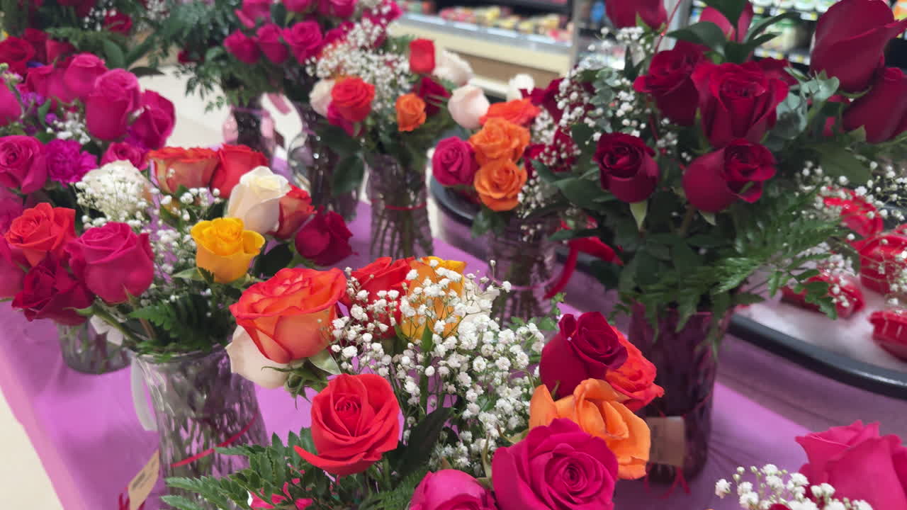 Valentinsblomster i en butik, rækker af vaser og buketter. Roser, tulipaner og andre arrangementer. Slowmotion.