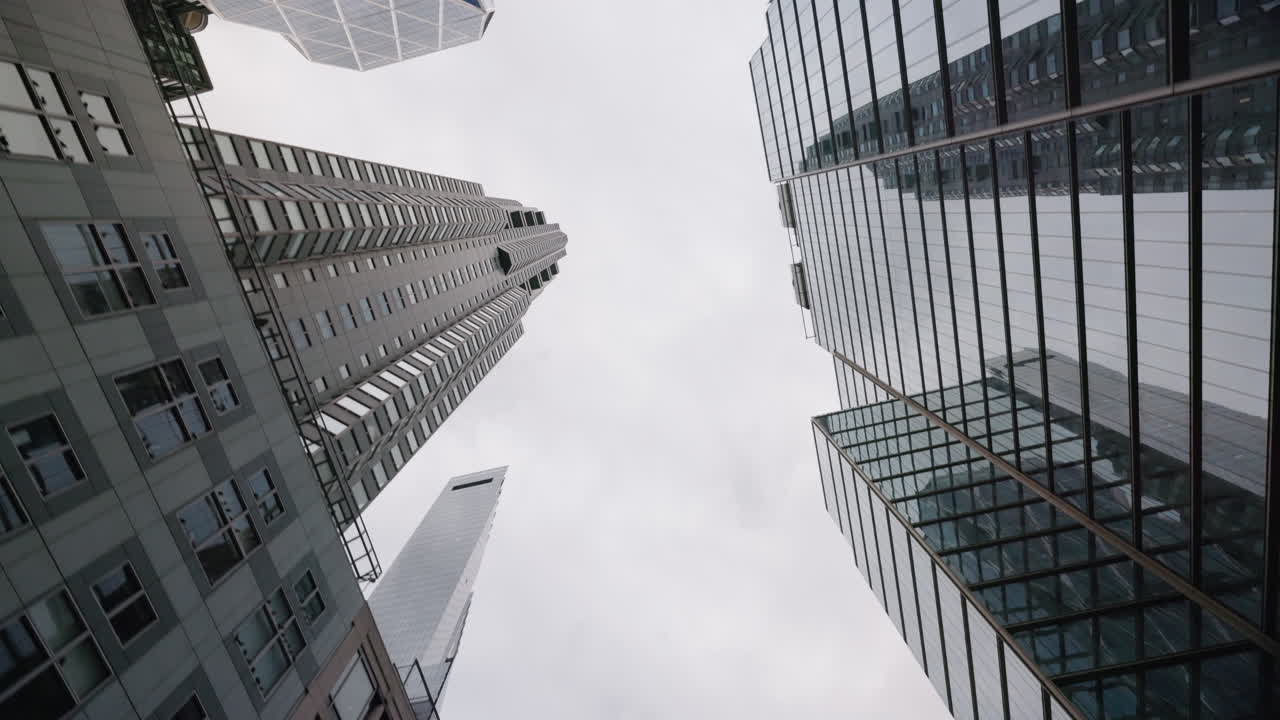 Vista em ângulo baixo de arranha-céus com céu nublado em Manhattan, Nova York, destacando arquitetura moderna e perspectiva urbana