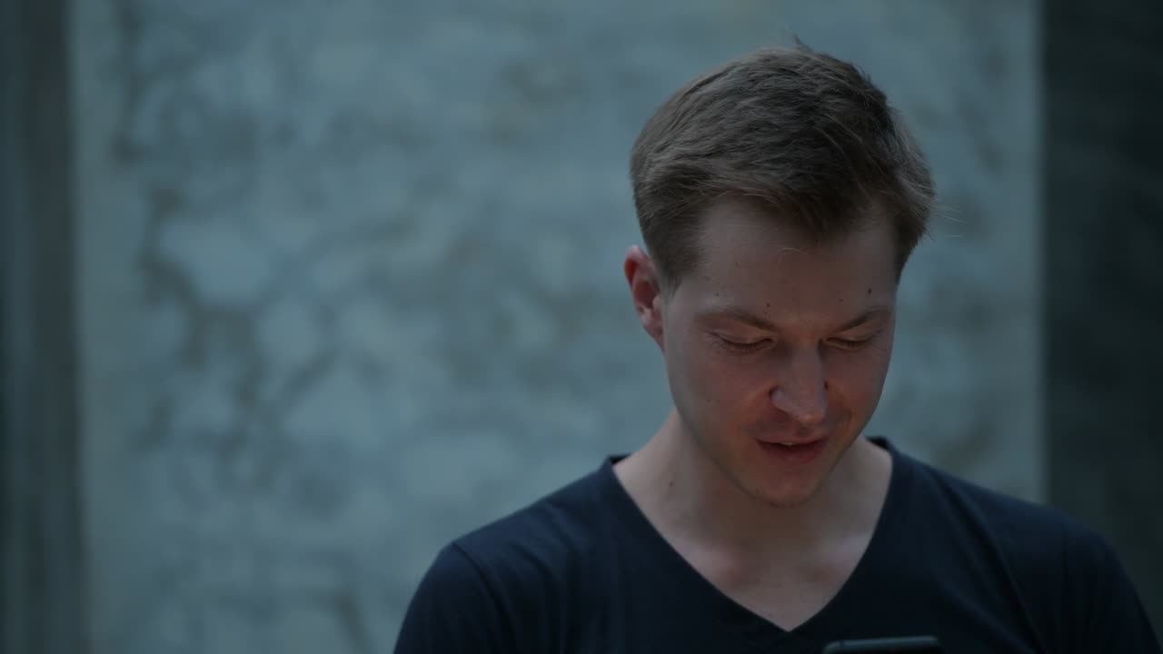 젊은 잘생긴 스칸디나비아 남자가 전화를 하면서 미소 짓고 있다