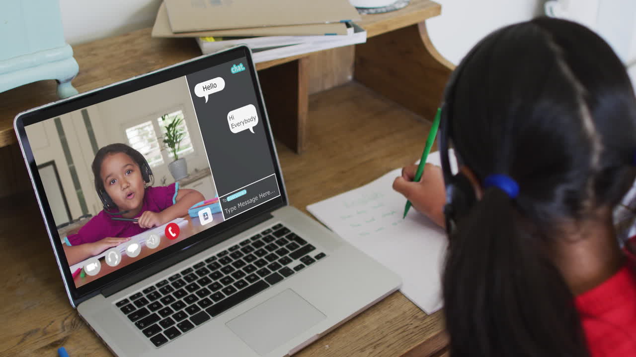 Schoolgirl using laptop for online lesson at home, with her colleague and web chat on screen