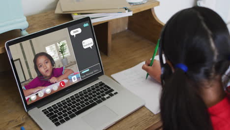 Schoolgirl-using-laptop-for-online-lesson-at-home,-with-her-colleague-and-web-chat-on-screen