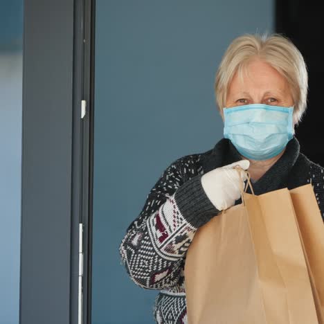 A-Portrait-Of-An-Elderly-Woman-In-A-Mask-Holding-Food-Bags