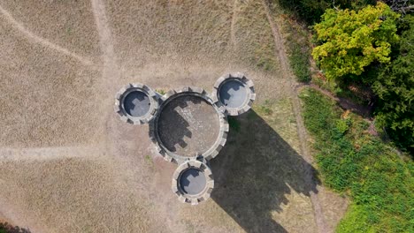 aerial top-down drone view of blaise castle, bristol, uk. the castle slowly rotates as shadows of its three turrets move clockwise, creating a striking time-like effect reminiscent of a giant clock