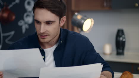 Focused-businessman-reading-documents-at-home-office.-Smiling-man-analyzing-data