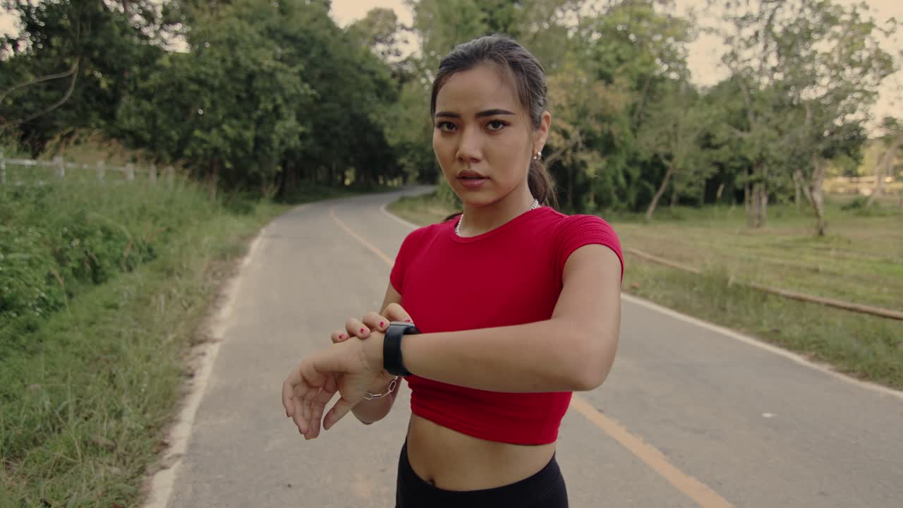 Woman Checking Smartwatch While Running Outdoors