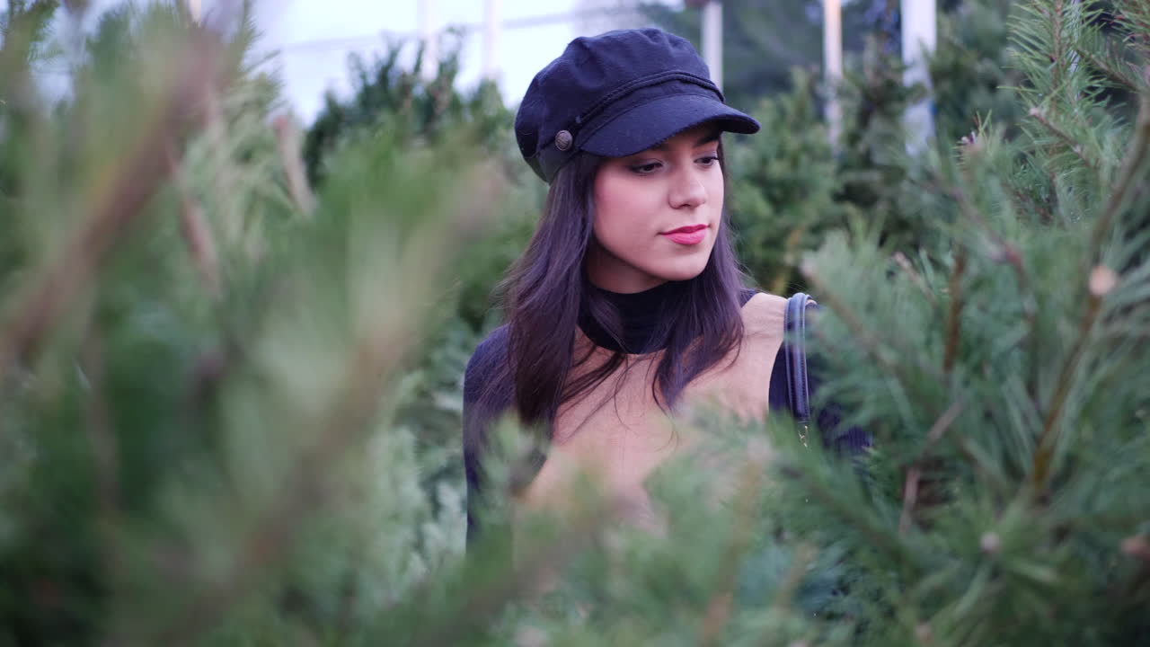 una mujer hispana en el espíritu navideño comprando árboles de navidad festivos