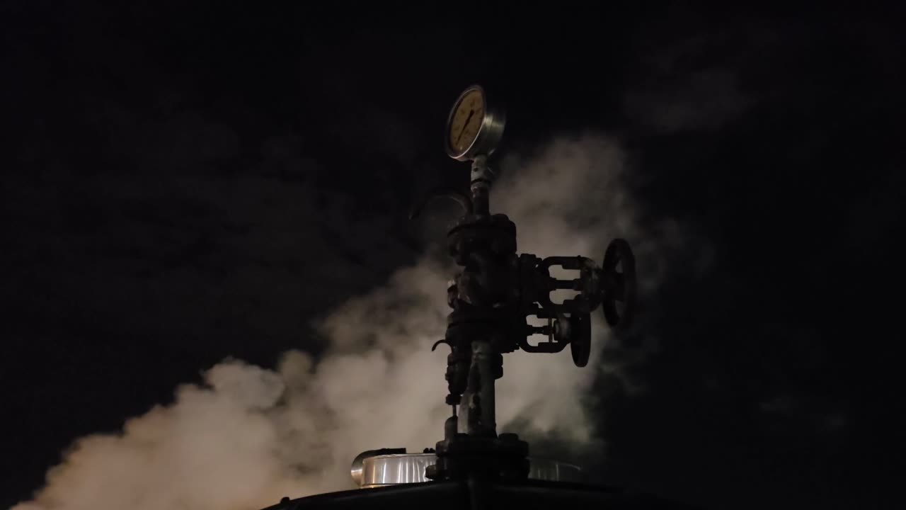 General shot at night in a chemical factory with starry sky and steam chimney releasing steam