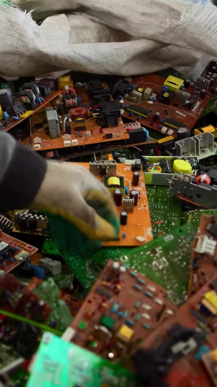 Gloved Worker Hands Sorting Circuit Boards Inside Recycling Workshop, Closeup Of Manual Inspection