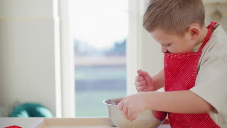 niño mezclando la masa de pan en un tazón de metal en la cocina