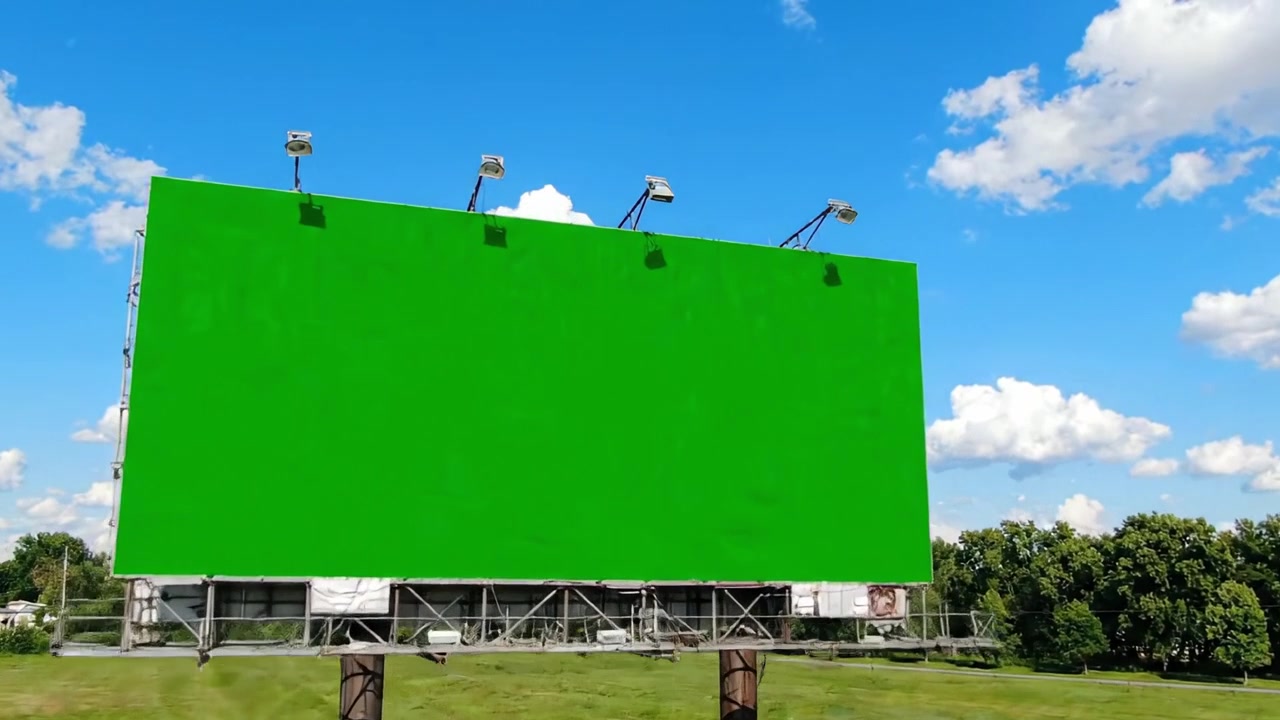 Et levende grønt reklameskilt står majestætisk på en åben mark under en klar blå himmel med bløde skyer, perfekt til grafisk fremvisning eller reklame.
