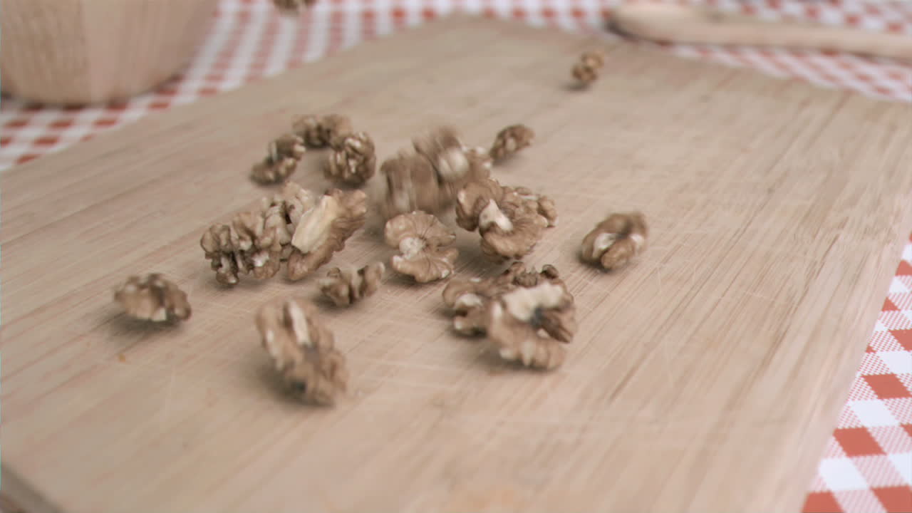 Gherigli di noce che cadono al super rallentatore su una tavola di legno