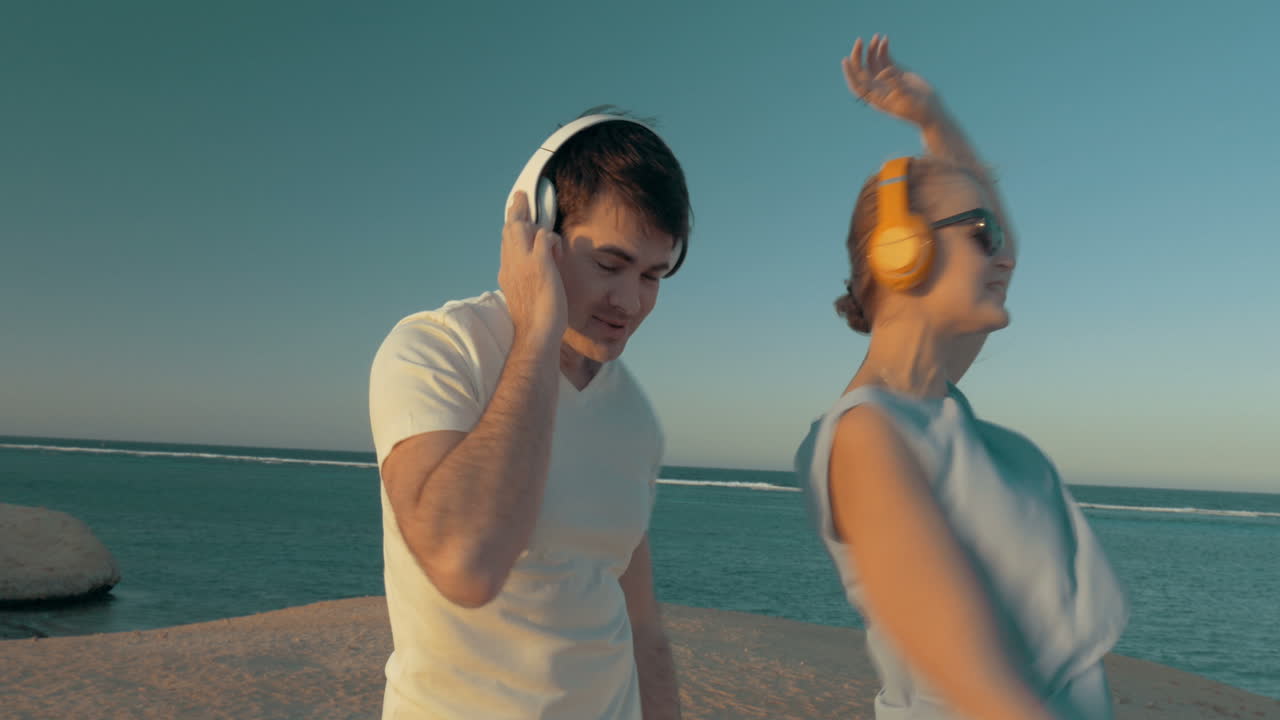 hombre y mujer disfrutando de la música en la playa
