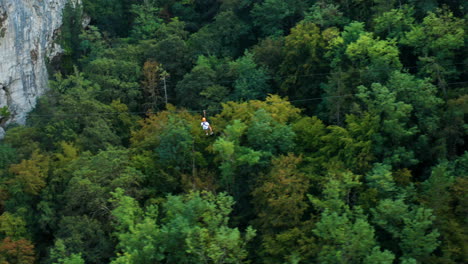 ziplining - man riding zip line over the town and green forest of pazin in istria, croatia