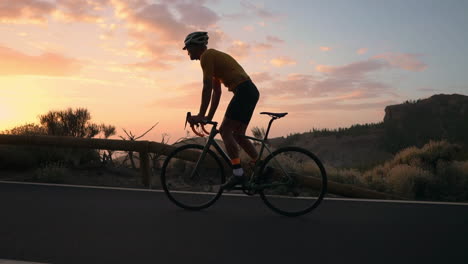 the athlete on a bike is showcased in slow motion as he rides a mountain serpentine, relishing the island's view, symbolizing a dedication to a healthy lifestyle during sunset