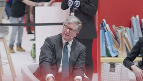older man, presenting slides at trade show, sitting down and looking up