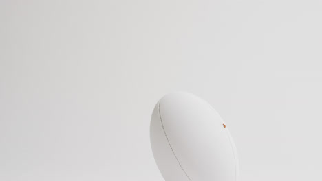 white rugby ball on kicking tee on white background with copy space, slow motion