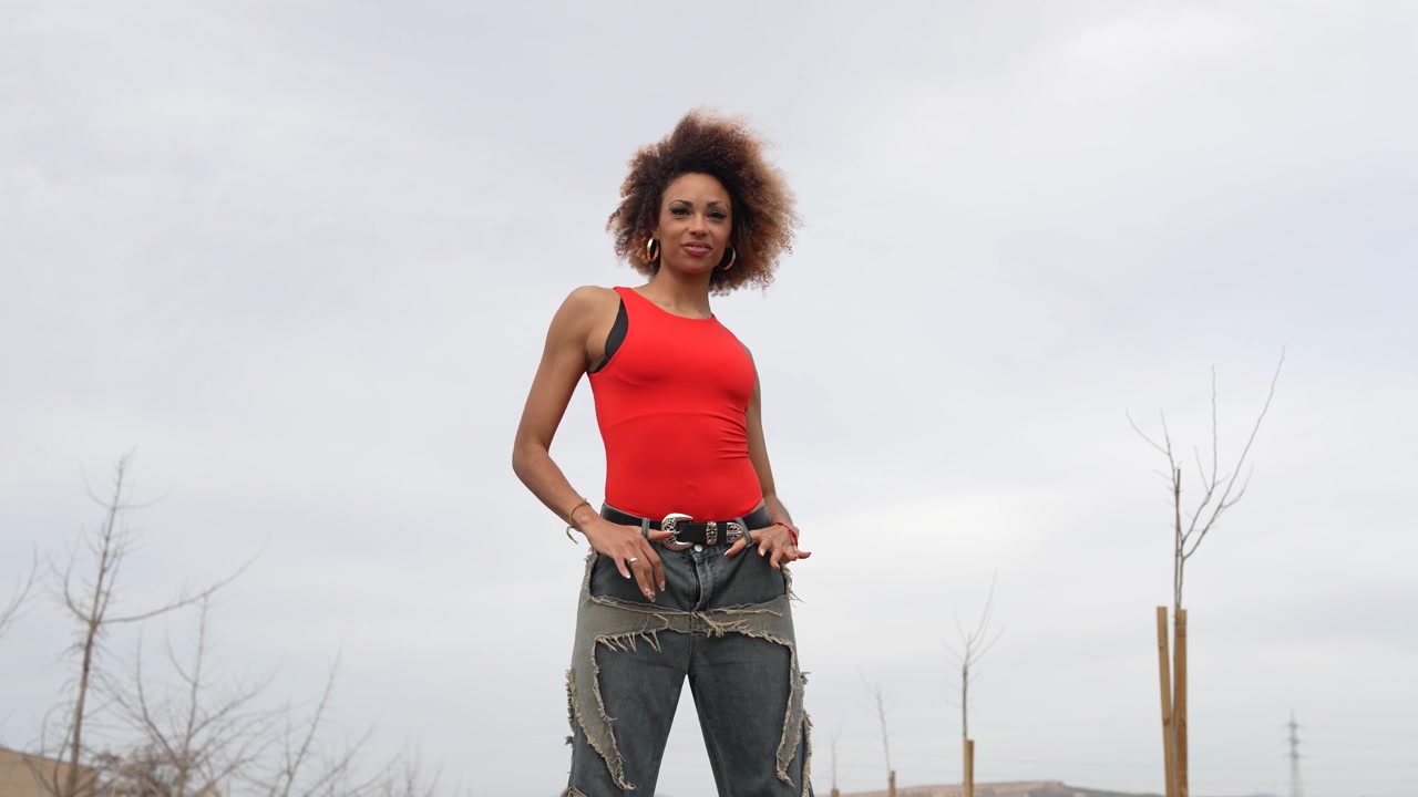 Eine selbstbewusste junge Frau steht stolz in einer wunderschönen Naturlandschaft, die sie umgibt.