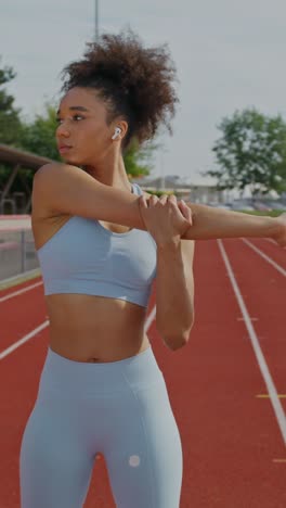 mujer estirándose en una pista de atletismo