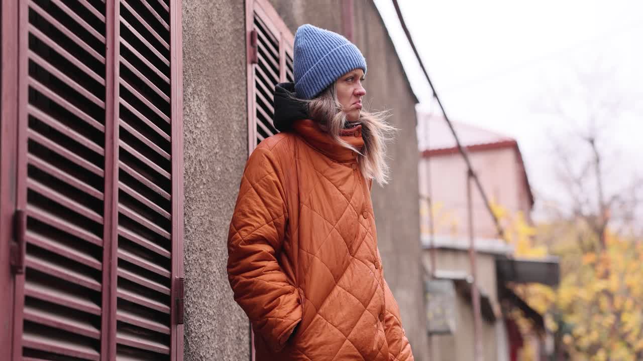 Woman in orange jacket and blue beanie outdoors