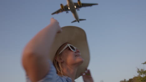 woman in hat smiling at landing airplane