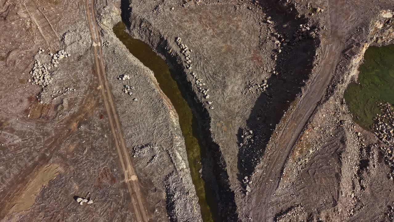 Cava di granito in funzione che mostra terreno scavato e flusso d'acqua vicino all'area di scavo durante le ore diurne