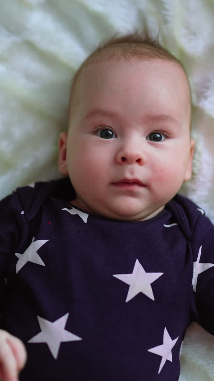 Cute baby on a bed. Adorable newborn child. Vertical video