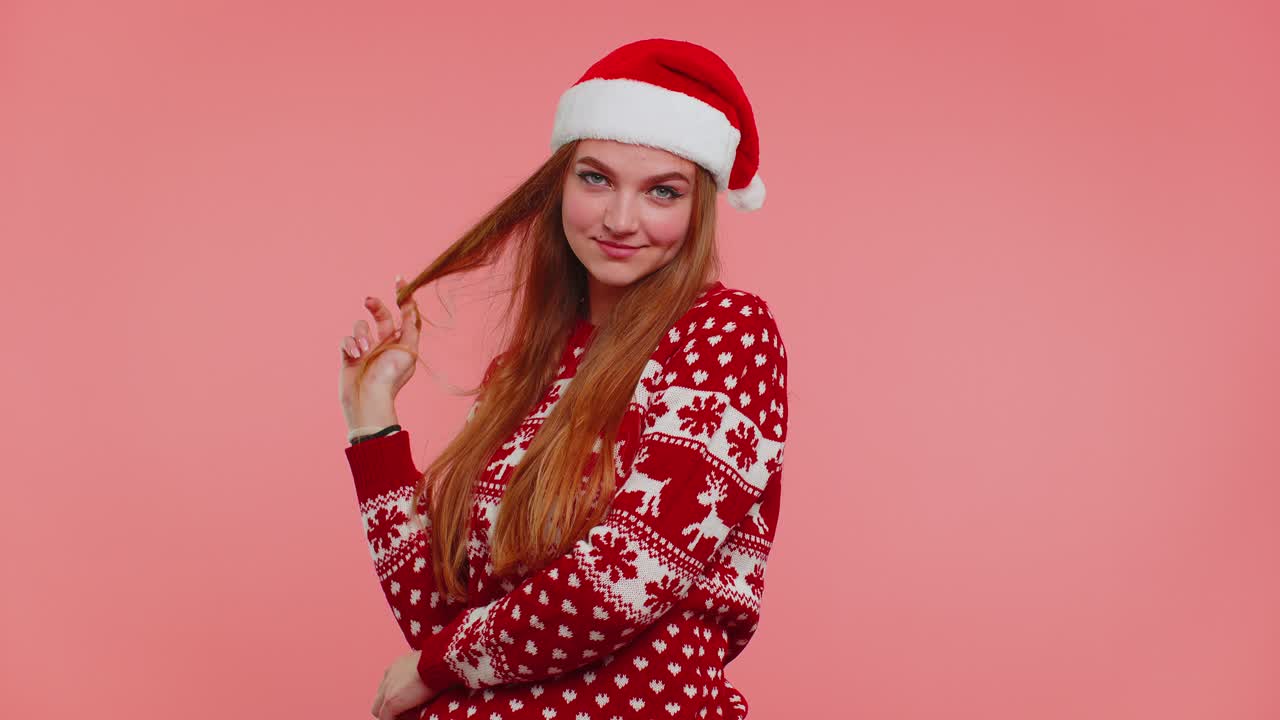 Cheerful lovely girl wears red christmas sweater and hat smiling looking at camera happy new year