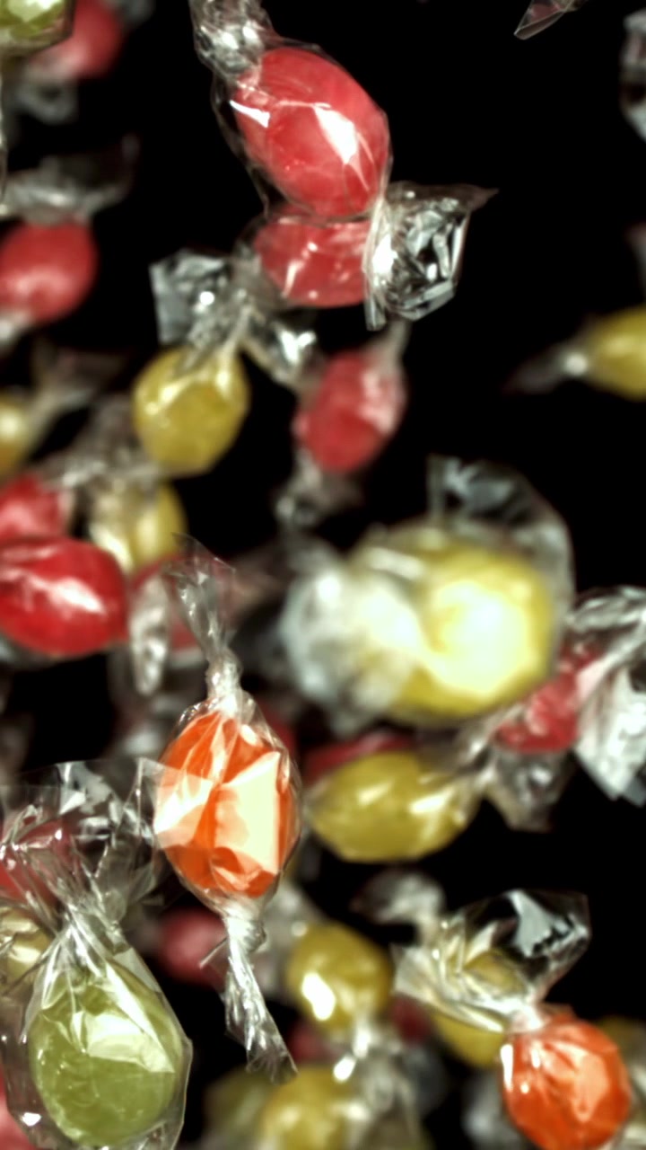 Caramelle incartate colorate che cadono al rallentatore