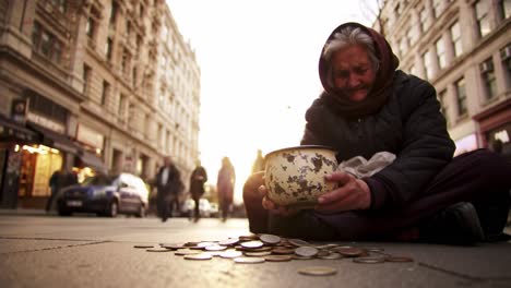 a woman sits on the street during the evening, gathering coins in a bowl as people walk by. the sunset creates a warm ambiance, highlighting the contrast of the bustling life around her.