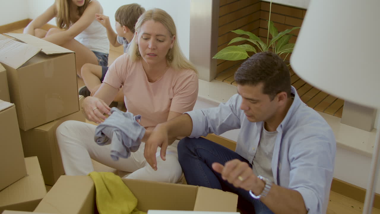 Excited couple taking clothes out of boxes after moving