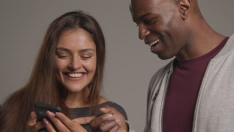 studio shot of group of friends with mobile phones celebrating winning money against grey background 3