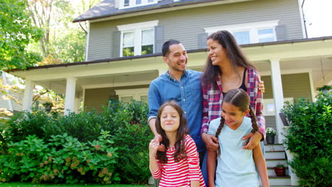 portrait of smiling family standing in front of their home